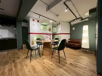 a room with a table and chairs and a couch at Tokyo Manekineko Stay \u62db\u304d\u732b\u3067\u6709\u540d\u306a\u8c6a\u5fb3\u5bfa\u99c5\u304b\u3089\u5f92\u6b699\u5206 \u30a2\u30fc\u30c6\u30a3\u30b9\u30c8\u5236\u4f5c\u306e\u62db\u304d\u732b\u30d9\u30c3\u30c9\u306e\u4e2d\u306b\u6cca\u307e\u308c\u308b\u5bbf in Tokyo