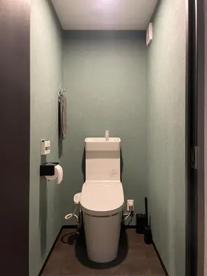 a bathroom with a toilet in a green wall at Tokyo Manekineko Stay \u62db\u304d\u732b\u3067\u6709\u540d\u306a\u8c6a\u5fb3\u5bfa\u99c5\u304b\u3089\u5f92\u6b699\u5206 \u30a2\u30fc\u30c6\u30a3\u30b9\u30c8\u5236\u4f5c\u306e\u62db\u304d\u732b\u30d9\u30c3\u30c9\u306e\u4e2d\u306b\u6cca\u307e\u308c\u308b\u5bbf in Tokyo