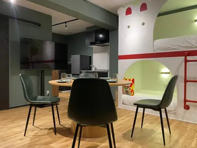 a room with a table and chairs and a bunk bed at Tokyo Manekineko Stay \u62db\u304d\u732b\u3067\u6709\u540d\u306a\u8c6a\u5fb3\u5bfa\u99c5\u304b\u3089\u5f92\u6b699\u5206 \u30a2\u30fc\u30c6\u30a3\u30b9\u30c8\u5236\u4f5c\u306e\u62db\u304d\u732b\u30d9\u30c3\u30c9\u306e\u4e2d\u306b\u6cca\u307e\u308c\u308b\u5bbf in Tokyo