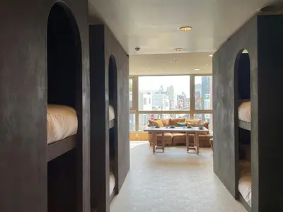 a room with beds and a dining room with a table at Tokyo Gallery Stay \u99c51\u5206\u3067\u8cb8\u5207 8\u4ebaOK\u306e\u30a2\u30fc\u30c6\u30a3\u30b9\u30c8\u5236\u4f5c\u306e\u30d9\u30c3\u30c9 \u685c\u3092\u898b\u4e0b\u308d\u305b\u308b\u90e8\u5c4b \u5546\u5e97\u8857\u3067\u8cd1\u3084\u304b in Tokyo
