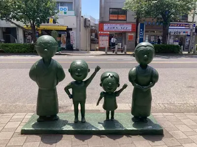 a statue of a family on the side of a street at Tokyo Gallery Stay \u99c51\u5206\u3067\u8cb8\u5207 8\u4ebaOK\u306e\u30a2\u30fc\u30c6\u30a3\u30b9\u30c8\u5236\u4f5c\u306e\u30d9\u30c3\u30c9 \u685c\u3092\u898b\u4e0b\u308d\u305b\u308b\u90e8\u5c4b \u5546\u5e97\u8857\u3067\u8cd1\u3084\u304b in Tokyo