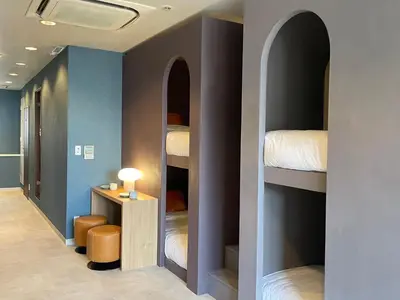 a hallway with four bunk beds in a room at Tokyo Gallery Stay \u99c51\u5206\u3067\u8cb8\u5207 8\u4ebaOK\u306e\u30a2\u30fc\u30c6\u30a3\u30b9\u30c8\u5236\u4f5c\u306e\u30d9\u30c3\u30c9 \u685c\u3092\u898b\u4e0b\u308d\u305b\u308b\u90e8\u5c4b \u5546\u5e97\u8857\u3067\u8cd1\u3084\u304b in Tokyo