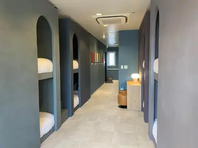 a hallway with blue walls and a hallway with beds at Tokyo Gallery Stay \u99c51\u5206\u3067\u8cb8\u5207 8\u4ebaOK\u306e\u30a2\u30fc\u30c6\u30a3\u30b9\u30c8\u5236\u4f5c\u306e\u30d9\u30c3\u30c9 \u685c\u3092\u898b\u4e0b\u308d\u305b\u308b\u90e8\u5c4b \u5546\u5e97\u8857\u3067\u8cd1\u3084\u304b in Tokyo