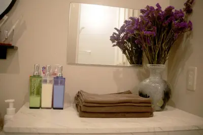 a bathroom counter with a vase of purple flowers and towels at aMIYAVI 2F in Tokyo