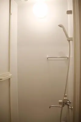a shower in a bathroom with a white wall at aMIYAVI 2F in Tokyo