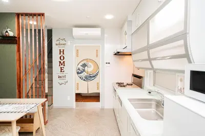 a kitchen with white counter tops and a table at Spacious 3-Story House with 2 Baths, 7 min to Metro direct to Akihabara Ueno Ginza in Tokyo