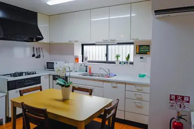 a kitchen with white cabinets and a wooden table at Akira Hiro House - Room203 in Tokyo