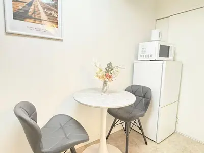 a small table with two chairs and a white refrigerator at Shinjuku Waseda B2 in Tokyo