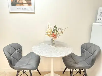 a table with two chairs and a vase of flowers on it at Shinjuku Waseda B2 in Tokyo