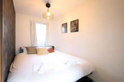 a bedroom with a bed with white sheets and a window at \u6e0b\u8c37\u30c6\u30e9\u30b9 \u6e0b\u8c37\u99c5\u5f92\u6b697\u5206 \u9ad8\u7d1a\u30de\u30f3\u30b7\u30e7\u30f3 \u30c6\u30e9\u30b9\u773a\u671b\u629c\u7fa4 in Tokyo