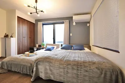 a bedroom with a large bed with blue pillows at \u6e0b\u8c37\u30c6\u30e9\u30b9 \u6e0b\u8c37\u99c5\u5f92\u6b697\u5206 \u9ad8\u7d1a\u30de\u30f3\u30b7\u30e7\u30f3 \u30c6\u30e9\u30b9\u773a\u671b\u629c\u7fa4 in Tokyo