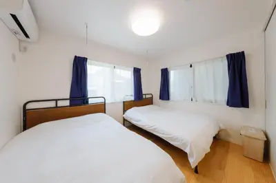 two beds in a small bedroom with blue curtains at Convertel Setagaya - Vacation STAY 45953v in Tokyo