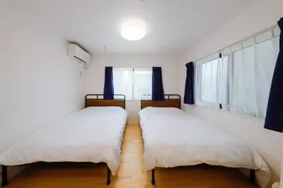 two beds in a bedroom with blue curtains at Convertel Setagaya - Vacation STAY 45953v in Tokyo