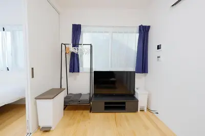 a room with a tv and a window with blue curtains at Convertel Setagaya - Vacation STAY 45953v in Tokyo