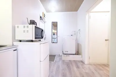 a white kitchen with a refrigerator and a tv at Belshaart Kamikitazawa - Vacation STAY 20402 in Tokyo