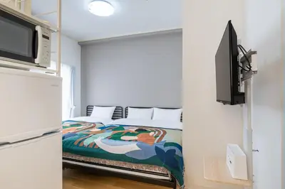 a bedroom with a bed and a tv in a room at 10-minute walk from Nakano Station Studio apartment \u5c0f\u677e\u30d3\u30eb31 in Tokyo