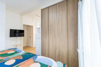 a bedroom with a bed and a wooden closet at 10-minute walk from Nakano Station Studio apartment \u5c0f\u677e\u30d3\u30eb31 in Tokyo