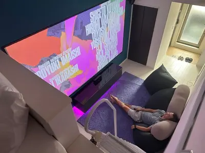 a person laying on a couch in front of a tv at Han Homes Omorihoncho in Tokyo