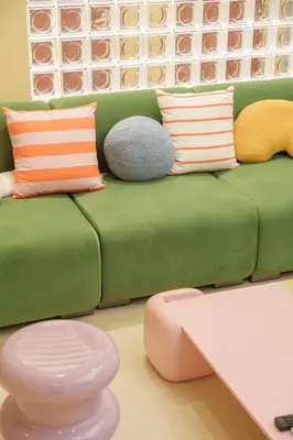 a green couch with colorful pillows on it at \u5bc5\u30db\u30c6\u30eb \u5fa1\u5f92\u753a Tora Hotel Okachimachi in Tokyo