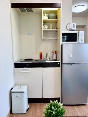 a small kitchen with a refrigerator and a sink at \u99c5\u5f92\u6b694\u5206 \u65b0\u5bbf\u99c57\u5206 \u30d0\u30f3\u30af\u30b7\u30fc\u30a2\u30fc\u30c8\u306e\u30b9\u30bf\u30a4\u30ea\u30c3\u30b7\u30e5\u30eb\u30fc\u30e0 in Tokyo