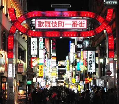 a busy city street with many signs and people at \u99c5\u5f92\u6b694\u5206 \u65b0\u5bbf\u99c57\u5206 \u30d0\u30f3\u30af\u30b7\u30fc\u30a2\u30fc\u30c8\u306e\u30b9\u30bf\u30a4\u30ea\u30c3\u30b7\u30e5\u30eb\u30fc\u30e0 in Tokyo