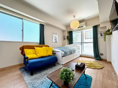 a living room with a bed and a blue couch at \u99c5\u5f92\u6b694\u5206 \u65b0\u5bbf\u99c57\u5206 \u30d0\u30f3\u30af\u30b7\u30fc\u30a2\u30fc\u30c8\u306e\u30b9\u30bf\u30a4\u30ea\u30c3\u30b7\u30e5\u30eb\u30fc\u30e0 in Tokyo
