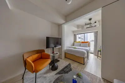 a bedroom with a bed and a chair and a television at Daffitto\u62bc\u4e0aI in Tokyo