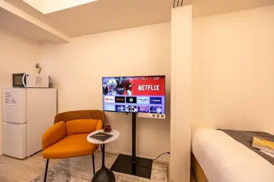 a room with a tv and a chair and a bed at Daffitto\u62bc\u4e0aI in Tokyo