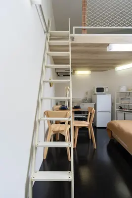 a loft bed with a desk and a ladder in a room at House Hotel Nakano TNA in Tokyo