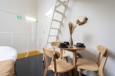a room with a table and two chairs and a ladder at House Hotel Nakano TNA in Tokyo