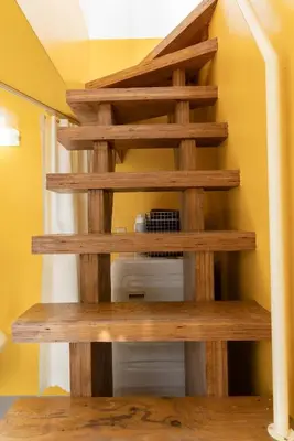 a wooden staircase in a room with a yellow wall at House Hotel Nakano TNA in Tokyo