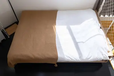 a bed with a white sheet on top of it at House Hotel Nakano TNA in Tokyo