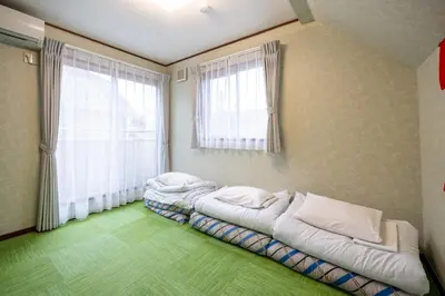 two beds in a room with two windows at Familia Kamata 1 in Tokyo