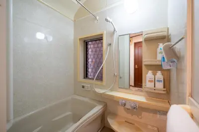 a bathroom with a tub and a toilet and a mirror at Familia Kamata 1 in Tokyo