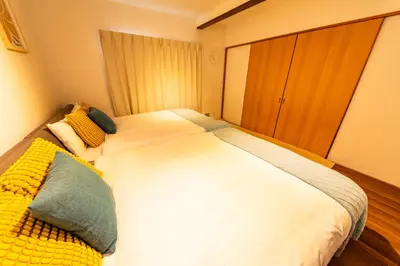a bedroom with a large white bed with yellow and green pillows at Lille Kameari in Tokyo