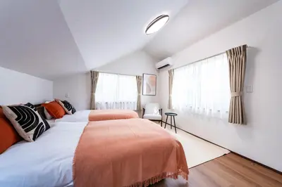 two beds in a room with white walls and windows at Lille Kameari in Tokyo