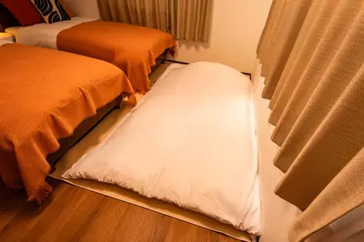 a room with two beds and a window with a mattress at Lille Kameari in Tokyo