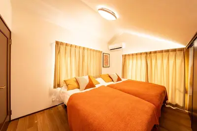 a bedroom with a large bed with orange sheets at Lille Kameari in Tokyo