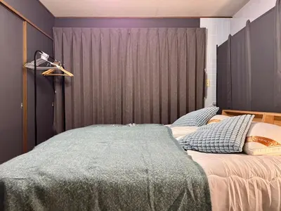 a bedroom with two beds and a gray wall at Oji kajiwara house in Tokyo