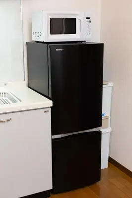 a microwave sitting on top of a black refrigerator at Kotori Itabashi in Tokyo