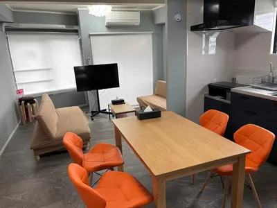 a living room with a table and orange chairs at Art House Katsushika in Tokyo