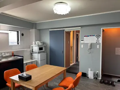 a kitchen with a wooden table and orange chairs at Art House Katsushika in Tokyo