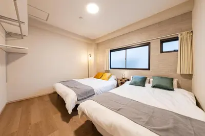 two beds in a room with two windows at Terrace Tokyo Otsuka in Tokyo
