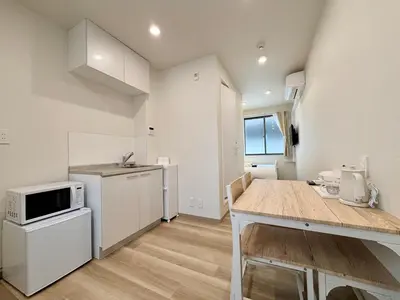 a kitchen with white cabinets and a table with a microwave at Hanshe Hotel Sumida No 3, Skytree & Asakusa 天空树 浅草 in Tokyo