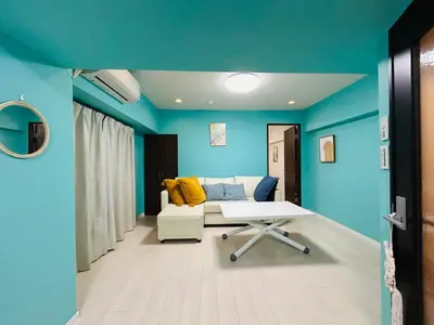 a living room with blue walls and a couch and a table at shinjuku kasa 1302 in Tokyo