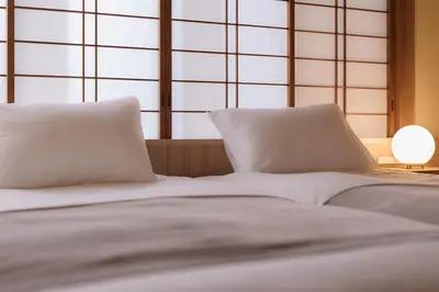 two beds with white pillows in a room with windows at Home suite Home Hatsudai - 1 stop from Shinjuku! Your urban hideaway 3BR 6beds in Tokyo