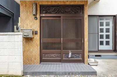 a brown door with a cat sitting in front of it at Home suite Home Hatsudai - 1 stop from Shinjuku! Your urban hideaway 3BR 6beds in Tokyo