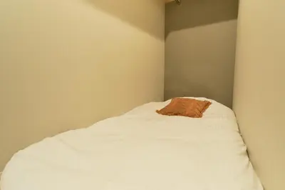 a small room with a bed with white sheets at monthly Grand Maison Natsumezaka in Tokyo