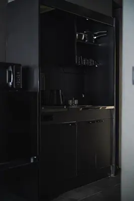 a kitchen with a black refrigerator and a sink at SLL Urban Suites Shibuya in Tokyo