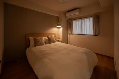 a bedroom with a large white bed with a window at Diamond Mansion Apartment Hotel in Tokyo